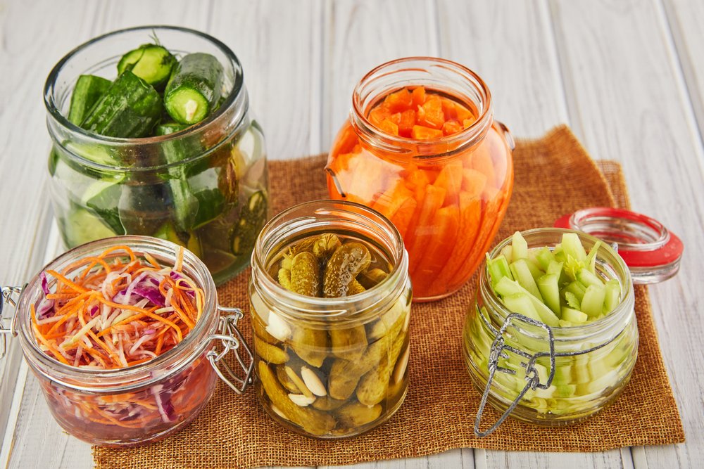 Glass jars filled with sliced fresh vegetables in bright colors. Fermented foods for gut health.